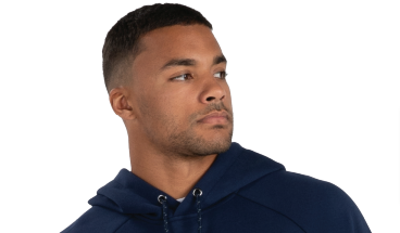 A man with short dark hair and a trimmed beard wears the LEGEND SHORT SLEEVE TECH FLEECE HOODIE in navy blue, featuring a zippered pocket, while looking off to the side against a plain white background.