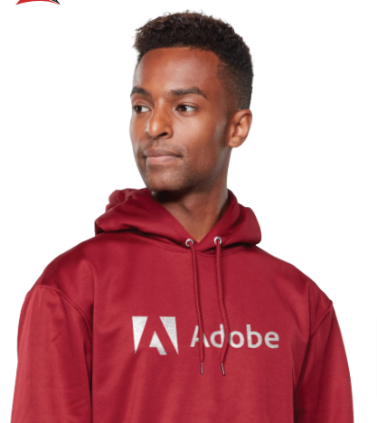 A person in a maroon WICKING FLEECE HOODIE with a white Adobe logo and text on the front, looking slightly to the side. The hoodie includes a self-lined hood for added comfort.